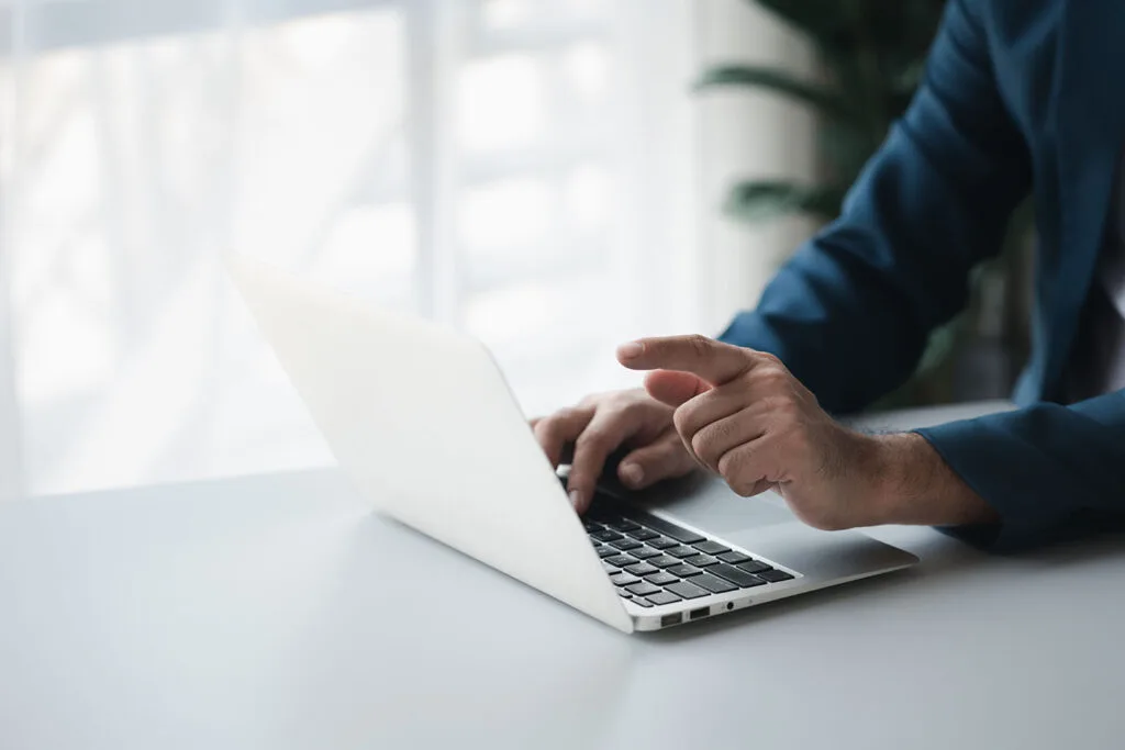 Quel est le prix d'un site internet ? 2 Mains d'un homme en train de taper à l'ordinateur - indique le prix d'un site internet